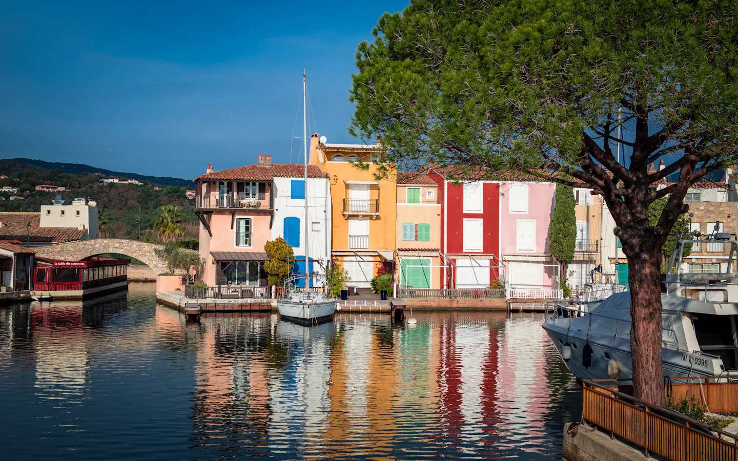 Maisons colorées de Port&nbsp;Grimaud au bord d'un canal, avec leurs reflets dans l'eau